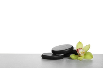 Black spa stones with orchid flower on white background. Space for text