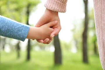 Little child holding hands with his mother outdoors, closeup. Family time - Powered by Adobe