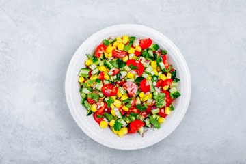 Fresh summer corn salad bowl with tomatoes, cucumbers, red onions and parsley.