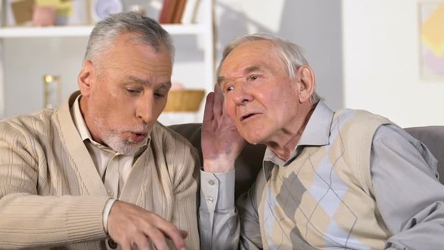 Senior retired man with hearing problem listening to friend, communication