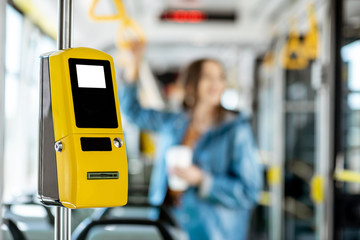 Yellow ticket machine in the modern tram with female passenger on the background