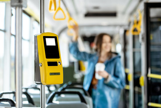 Yellow ticket machine in the modern tram with female passenger on the background