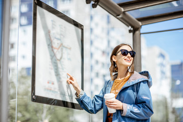 Woman looking on the scheme of public transport while standing at the tram station outdoors