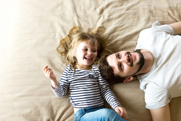 Handsome young father and happy daughter have fun together.