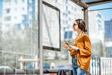 Woman looking on the scheme of public transport while standing at the tram station outdoors