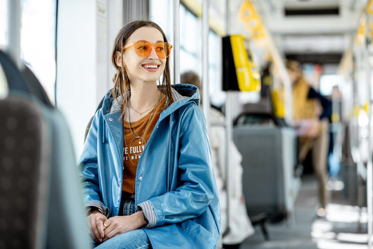Young stylish woman dressed brightly enjoying trip at the public transport, sitting in the modern tram
