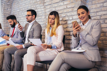 Business people waiting for job interview. They use their phones while waiting