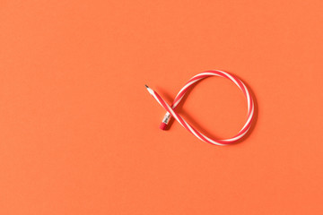 Flexible pencil . Isolated on orange background. Bending pencil.