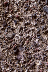 Background texture of the surface of a brown stone of a vulcanic origin. View from above, cropped shot, vertical, close-up, nobody. Concept of design and nature.