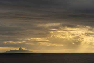 East Nusa Tenggara Island, Indonesia - February 24, 2019: Early morning at sunrise. Southside coast off Sessok in Savu Sea under cloudscape with yellow and darker patches. Dark sea, hill silhouette of