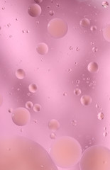 Drops of oil in water on a colored background. Bright background with pink circles of different sizes. Blur, vertical, place for text, monophonic. Design concept.