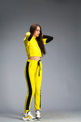 Portrait of a young beautiful brunette woman in yellow tracksuit