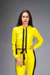 Portrait of a young beautiful brunette woman in yellow tracksuit