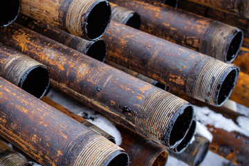 Salvaged pipes and casings are lined up on racks in storage on a California oil lease. Drill pipes with oil drops