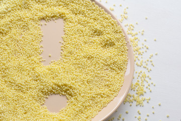 Dry couscous on a plate on a white background. Spilled couscous.