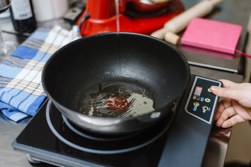heat the oil in a frying pan for cooking. Woman pours olive oil into the pan