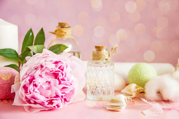 Transparent glass bottles with cosmetic, bath bombs, shells, candles, fresh pink flowers, white towel, cotton boxes on a pink background. The concept of natural cosmetics and spa skin care. Copy space