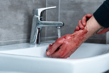 partial view of man washing bleeding hands in sink