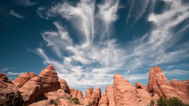 Red rock sandstone fins in the Utah Desert, as clouds move through the sky in time lapse at Arches National Park.