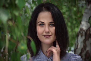 Young woman with perfect skin in green foliage in spring. Presenting your product. Face whom trust. Her mouth open with smile