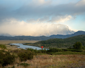 View of Mountains, grass meadow, and river during sunrise in Patagonia Chile, Torres del Paine  with lone figure in distance 