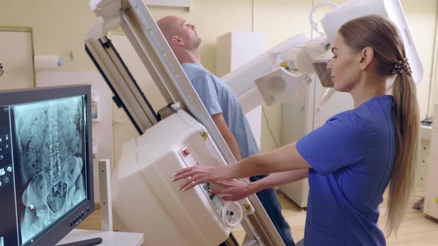 Beautiful Female Technician ajusts X-ray Machine, man lying