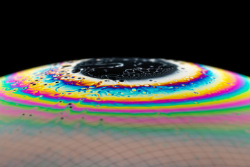 A macro shot of a soap bubble with a beautiful and colorful structure - black background