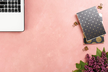 Cropped image of laptop keyboard & lilac flowers in minimal arrangement on white table top background. Feminine flat lay composition with pc notebook computer and purple bouquet. Close up, copy space