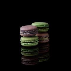 Multi-color macarons on the black background. Side view. Blank space.