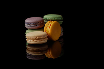 Multi-color macarons on the black background. Side view. Blank space.