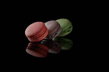 Multi-color macarons on the black background. Side view. Blank space.