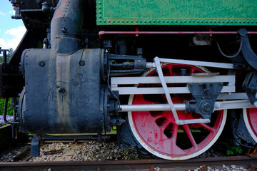 Fototapeta na wymiar Vintage steam locomotive detail with cranks and red wheels