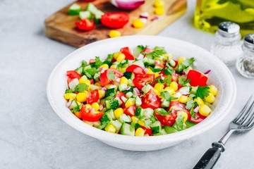 Fresh summer corn salad bowl with tomatoes, cucumbers, red onions and parsley.