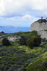 Summer sunny morning on the island of Santorini, Greece. Blue sea, blue sky with clouds against the background of the island. Euro trip. .Volcanic island in the Aegean Sea.