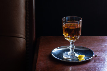 Brandy, Whiskey, Amaretto, or any Brown Liqueur Drink Served Neat with Lemon Twist in Dark Luxurious Bar
