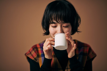  暖かい飲み物を飲む若い女性