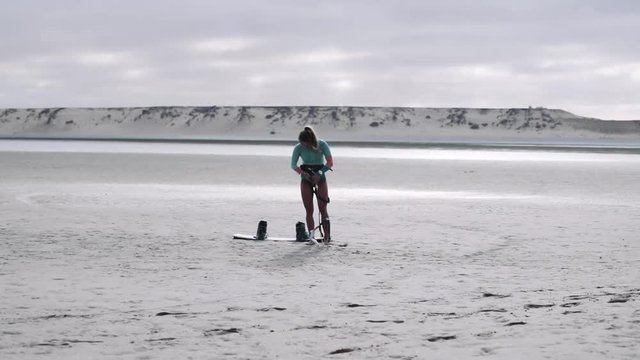 Kiteboarder with Equipment Standing on Sand