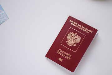 foreign red passport with a card phone white headphones and different coins on a white background