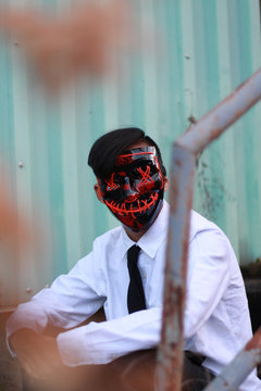 man wearing black and red mask while sitting on staie