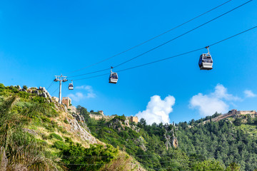 Cabins on the cable car in the background of mountains and bright blue sky.