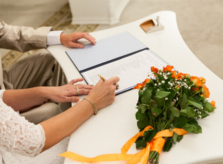 Hands of Caucasian wedding people signing document on wed ceremony, close up view