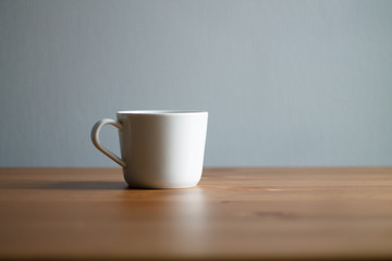 white coffee mug on wooden table and light background