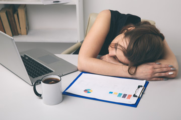 Tired female office worker sleeping at her workplace infront of computer