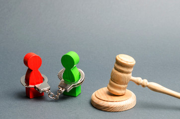 Two people are handcuffed to each other and stand near the judge's gavel. Dispute resolution...