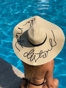 woman sitting next to pool wearing sun hat