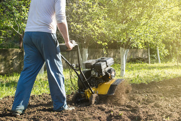 A man plowing a soil by motor cultivator perspective view