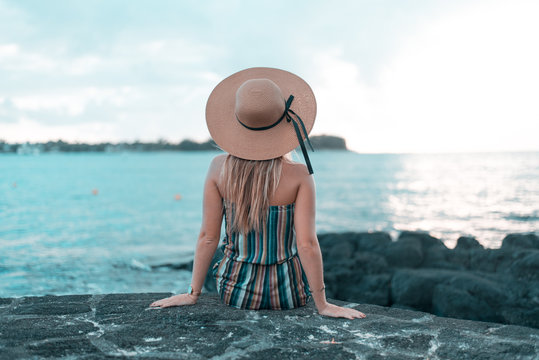 woman sitting on rock facing shore