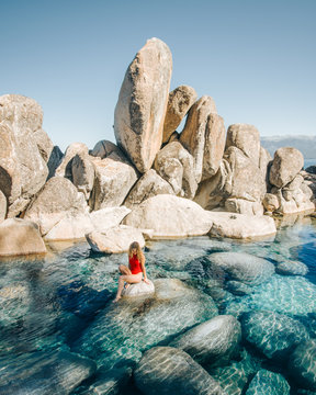 woman sitting on rock surrounded by water