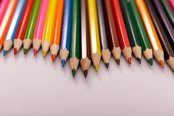 Bunch of colored pencils on white wooden table. Top view. Large set of colored pencils pointing up.