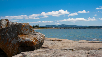 Illa de Arousa, Galicia, Spain, Beautiful pebble beach with algae on the shore and blue sky with clouds